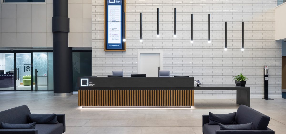 interior of a company reception area, with desk and black sofas